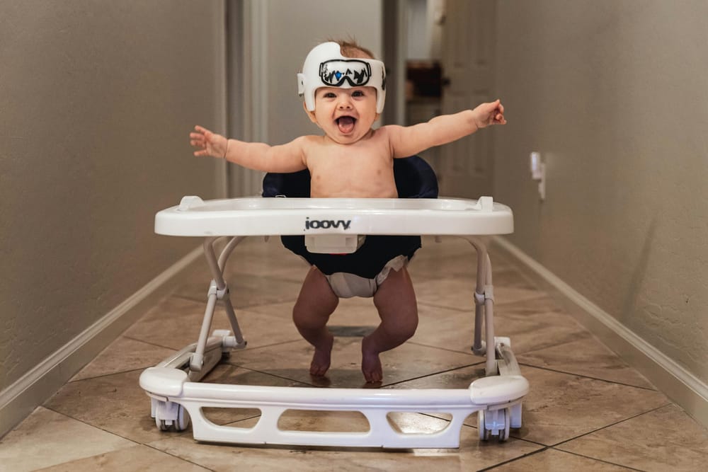 joyful baby in a baby walker with arms outspread.